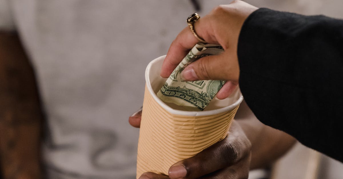 A hand giving money to a person holding a cup, reflecting generosity and support.